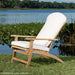 Westminster Teak Adirondack Lounger with white cushions placed on grass near a lake