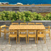 Westminster Teak Horizon 11pc Teak Dining Set is at an angle on a patio, with a scenic ocean and hillside view behind the table and chairs