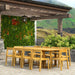 Westminster Teak Horizon 11pc Teak Dining Set is shown from the side under a covered patio, with the long teak table and matching chairs set in an outdoor garden space
