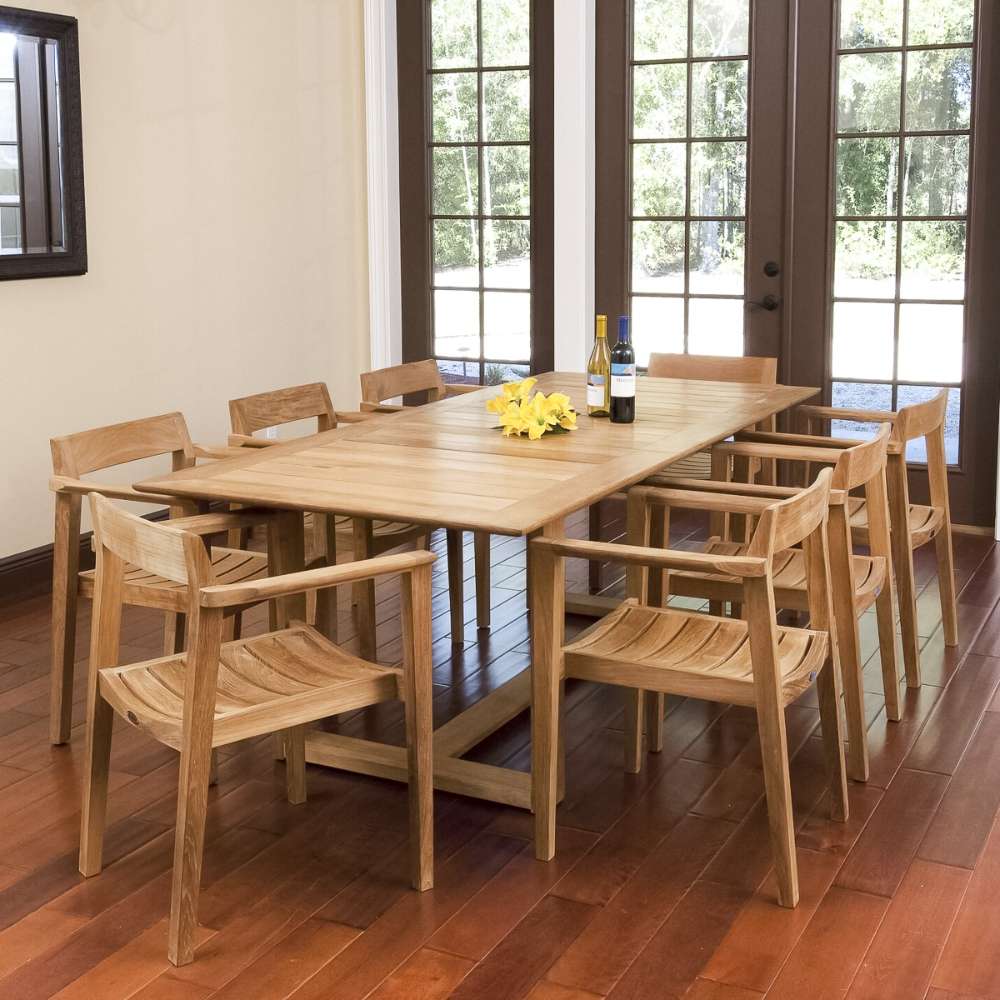 Westminster Teak Horizon 9pcs Teak Dining Set displayed indoors on wooden flooring, with a teak table and chairs arranged neatly near glass doors, decorated with flowers and wine bottles