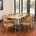 Westminster Teak Horizon 9pcs Teak Dining Set displayed indoors on wooden flooring, with a teak table and chairs arranged neatly near glass doors, decorated with flowers and wine bottles