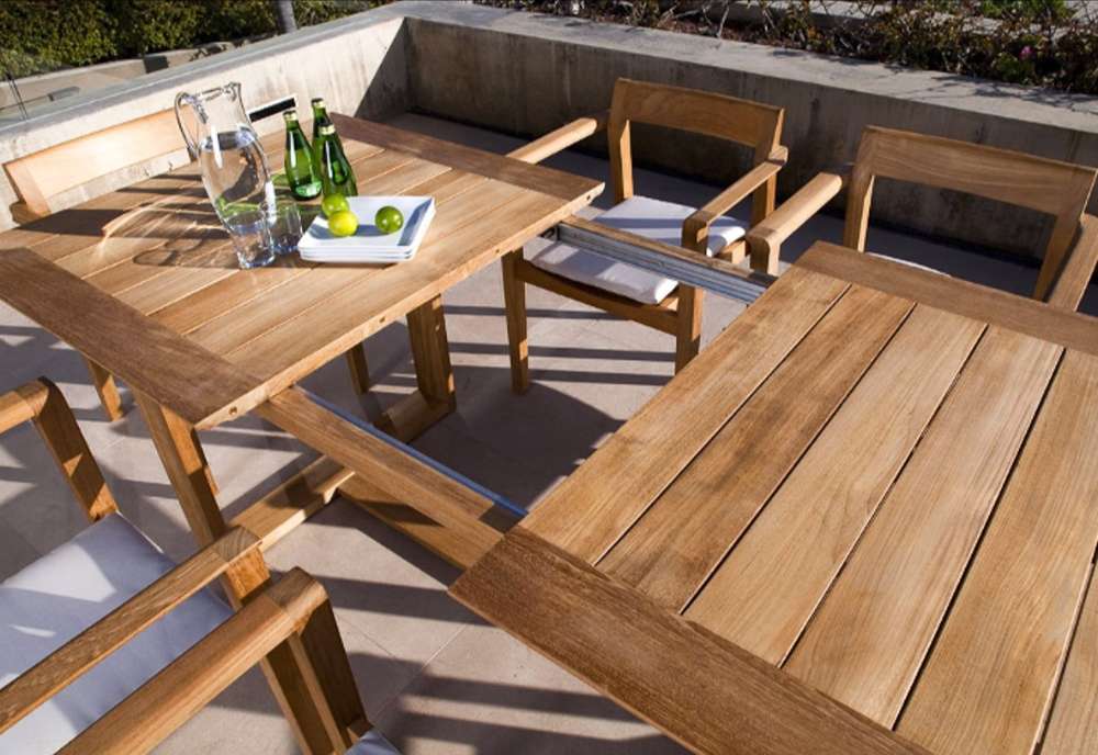 Westminster Teak Horizon 9pcs Teak Dining Set partially extended table shown outdoors, revealing the sliding extension leaf and sturdy teak construction with chairs around it