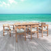 Westminster Teak Horizon 9pcs Teak Dining Set placed on a wooden deck by the ocean, showing the full teak table and chairs in a bright seaside setting