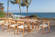 Westminster Teak Horizon 9pcs Teak Dining Set placed on an outdoor balcony by the ocean, with cushioned chairs around a teak table holding drinks and limes