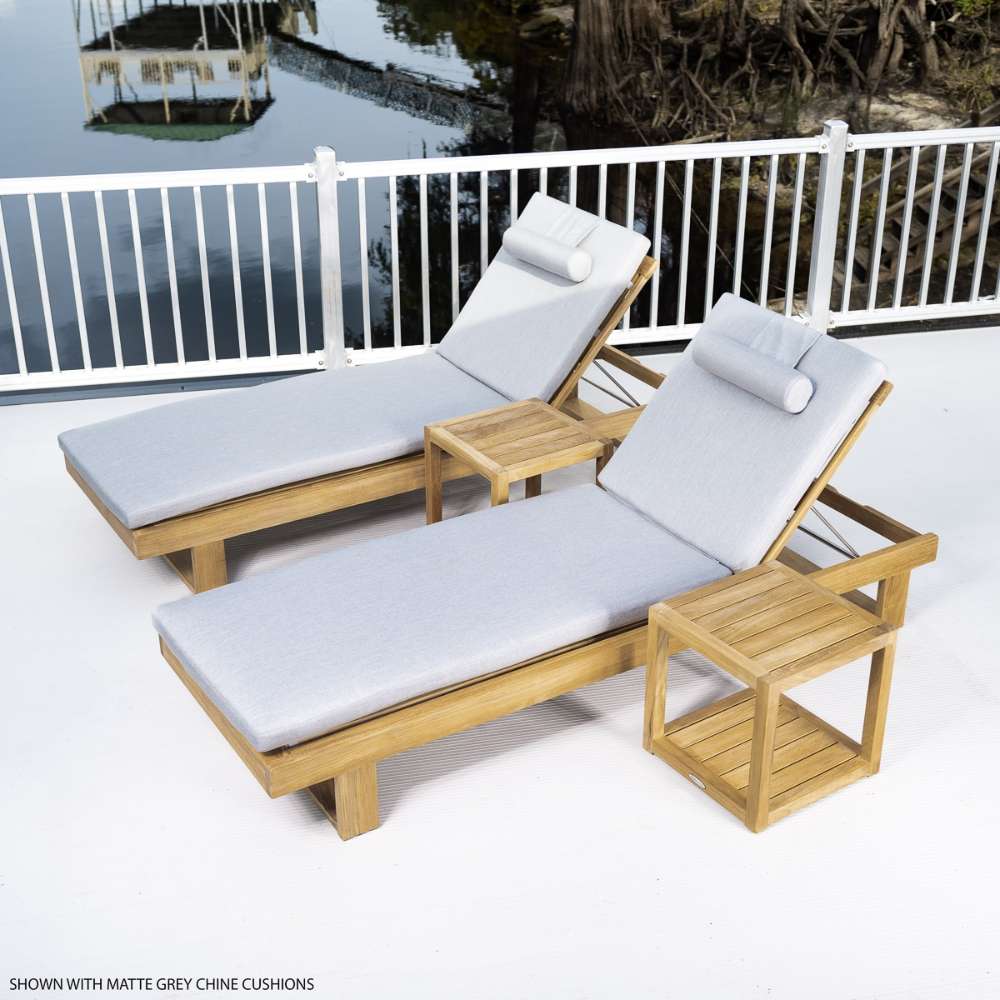 Westminster Teak Horizon Double Chaise and Side Table Set shown on a deck by calm water with two gray-cushioned loungers and small teak tables beside a white railing