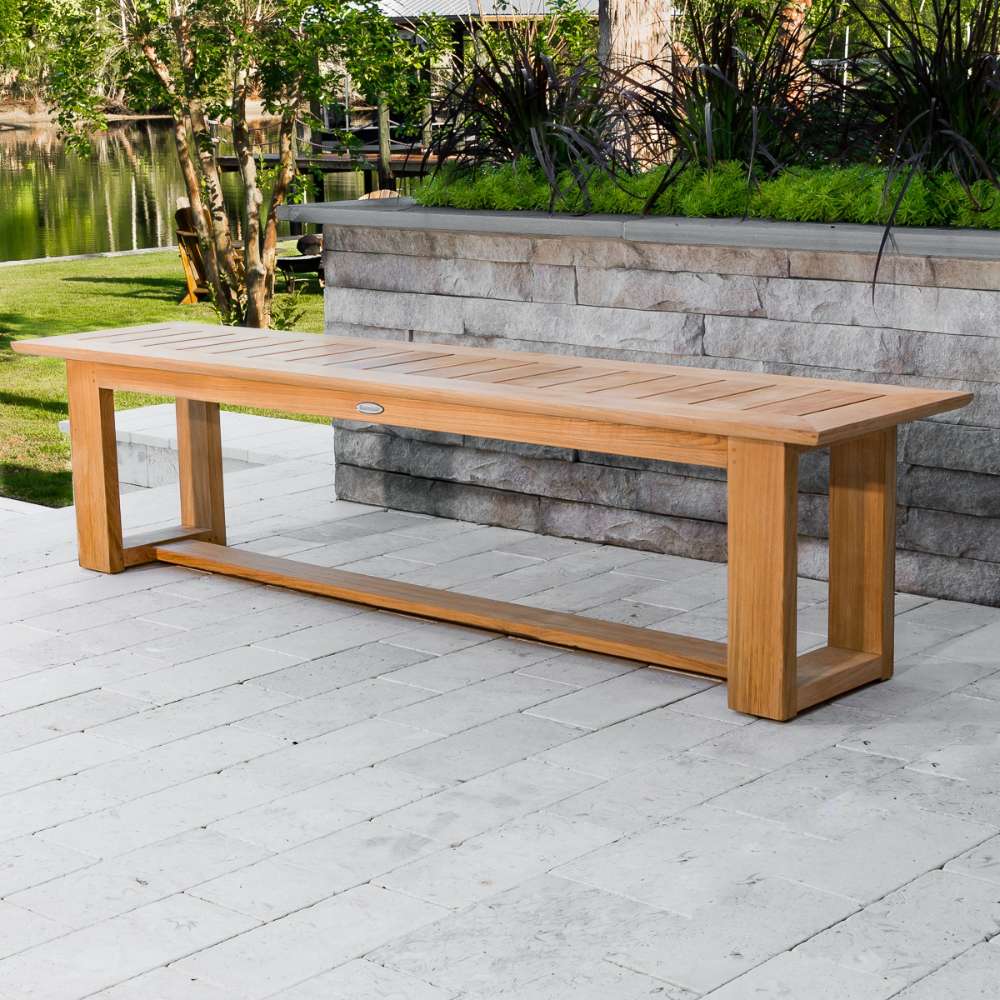 Westminster Teak Horizon Teak Dining Picnic Set backless bench placed on a patio with greenery and a lake view