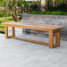 Westminster Teak Horizon Teak Dining Picnic Set backless bench placed on a patio with greenery and a lake view