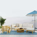 Westminster Teak Kafelonia 6pc Sofa Sectional Set on a terrace with white cushions, teak tables, plants, and an umbrella