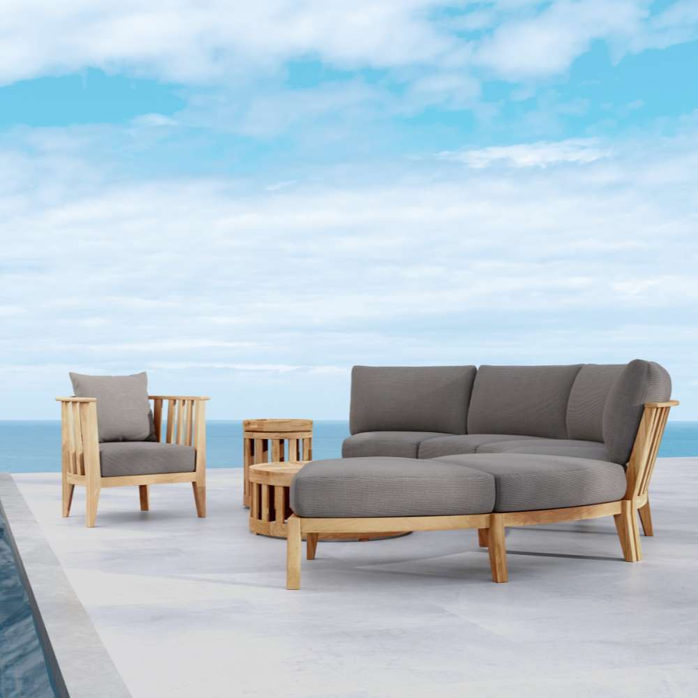 Westminster Teak Kafelonia 6pc Sofa Sectional Set with gray cushions, lounge chair, and tables on a patio overlooking the ocean