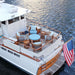 Westminster Teak Kafelonia Club Chair as part of a teak lounge set on a boat deck with blue cushions and ocean surroundings