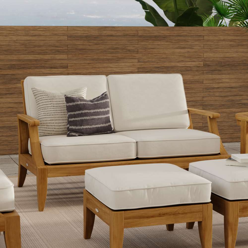 Westminster Teak Laguna Love Seat is styled on a patio with matching ottomans, showcasing a cozy outdoor seating arrangement with neutral cushions