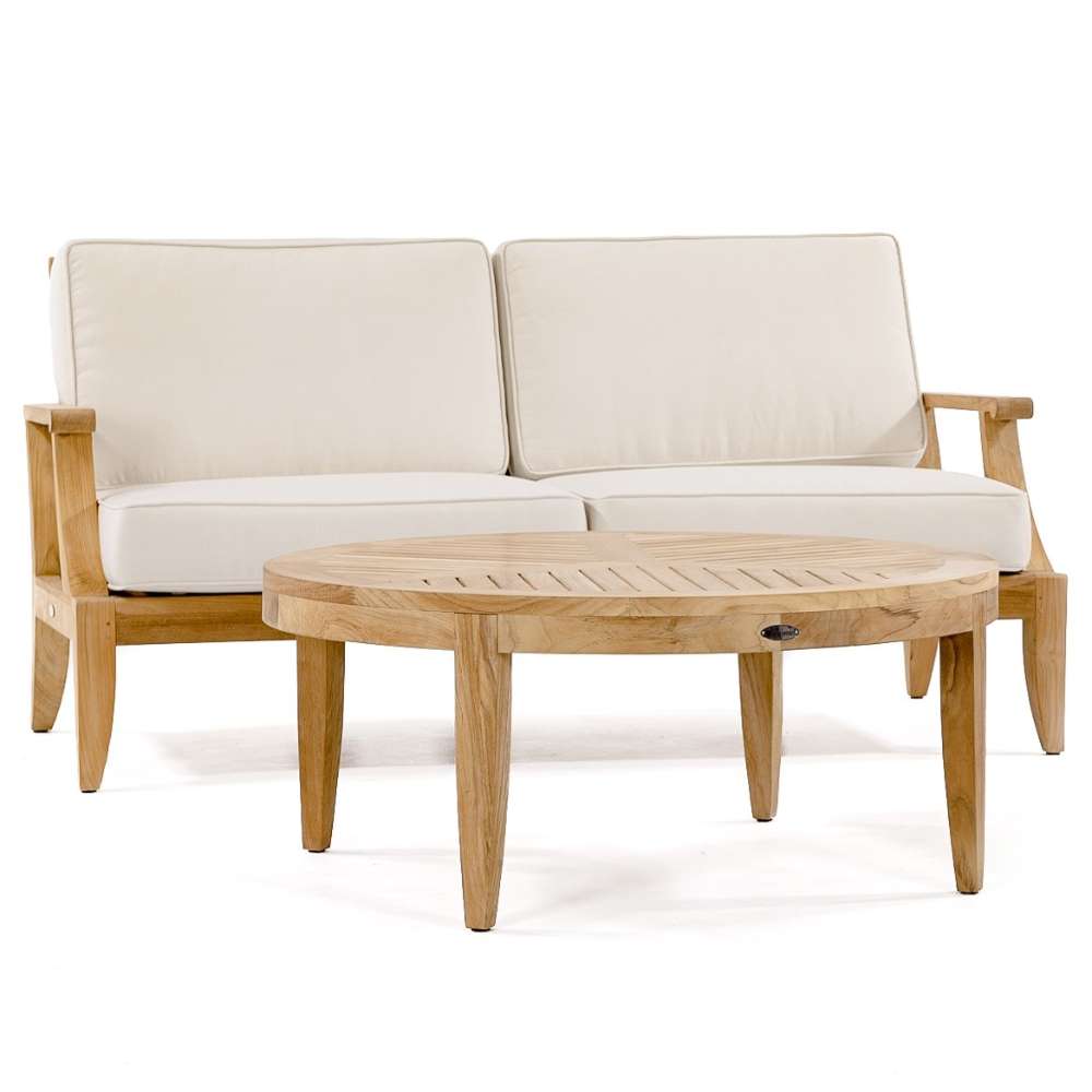 Westminster Teak Laguna Sofa is displayed with light cushions and a matching round teak coffee table in front, all set against a plain white background