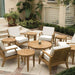 Westminster Teak Laguna Teak Coffee Table is part of a large outdoor patio set, surrounded by multiple chairs, side tables, and greenery