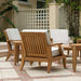 Westminster Teak Laguna Teak Lounge Chair from the back in an outdoor seating area with matching chairs, teak tables, and white cushions