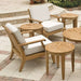 Westminster Teak Laguna Teak Lounge Chair in an outdoor patio scene with two matching cushioned chairs and several round teak side tables