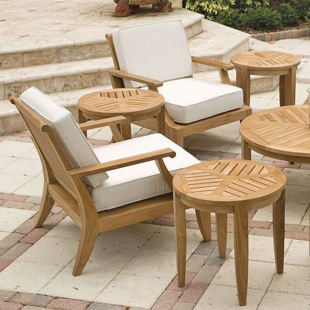 Westminster Teak Laguna Teak Side Table is part of an outdoor seating set, placed beside cushioned chairs on a stone patio