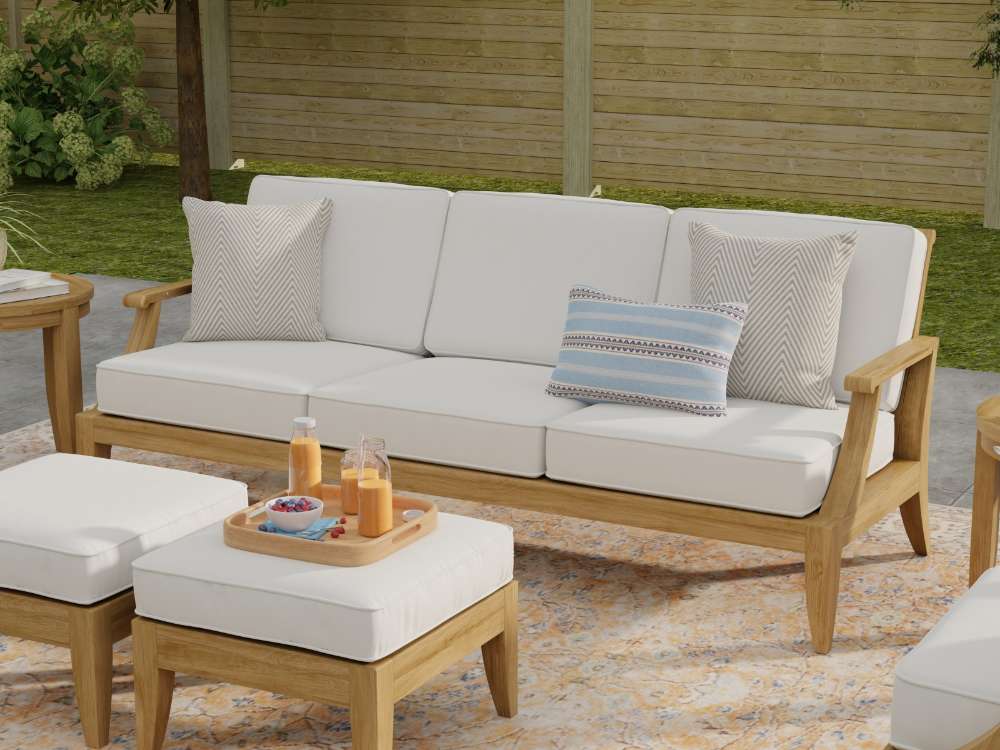 Westminster Teak Large Laguna Sofa on a patio with white cushions, accent pillows, and matching ottomans nearby