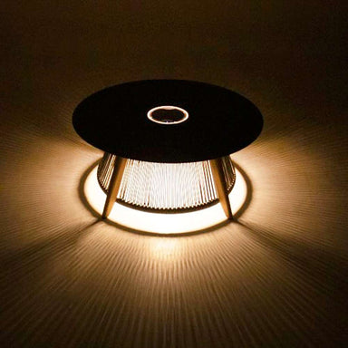 Westminster Teak Luna Coffee Table glowing at night with warm light shining through its rope base