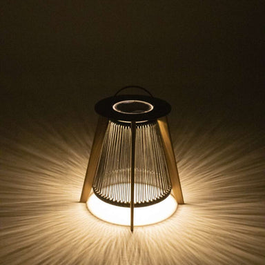 Westminster Teak Luna Large Lantern glows warmly in the dark, casting soft, radial light patterns through its vertical rope design onto the surrounding surface