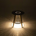 Westminster Teak Luna Round Side Table is displayed glowing in the dark, casting soft light patterns on the ground from its illuminated base