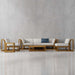 Westminster Teak Maya 6pc Lounge Sofa Set styled in a room setting with a grey wall, featuring light cushions and a single blue accent pillow on the sofa