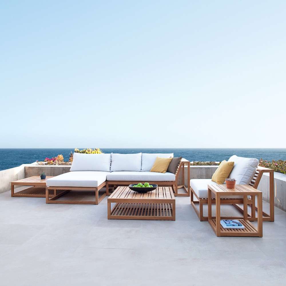 Westminster Teak Maya Chaise complements a large outdoor sectional setup with matching teak furniture, cushions, and tables overlooking the ocean