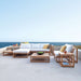 Westminster Teak Maya Chaise complements a large outdoor sectional setup with matching teak furniture, cushions, and tables overlooking the ocean