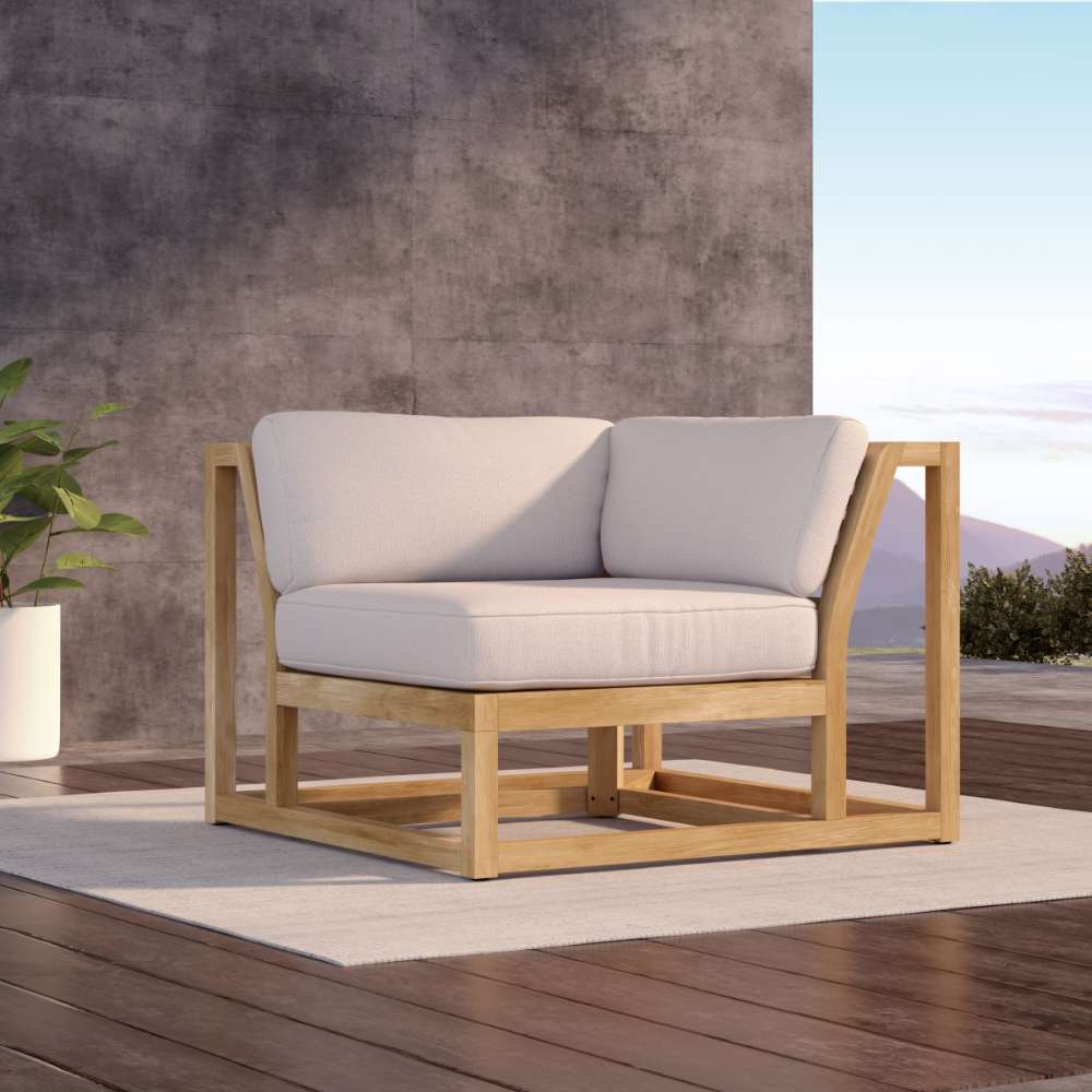 Westminster Teak Maya Corner Sectional is shown on an outdoor patio, highlighting its warm teak frame and plush light cushions in a relaxed, sunlit setting