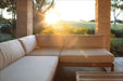 Westminster Teak Maya Right Side Sectional outdoor setup on a patio with soft cushions and a sunset view over a grassy field