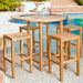 Westminster Teak Somerset Backless Bar Stool is arranged around a patio bar table holding a glass pitcher and cups near a pool and hot tub