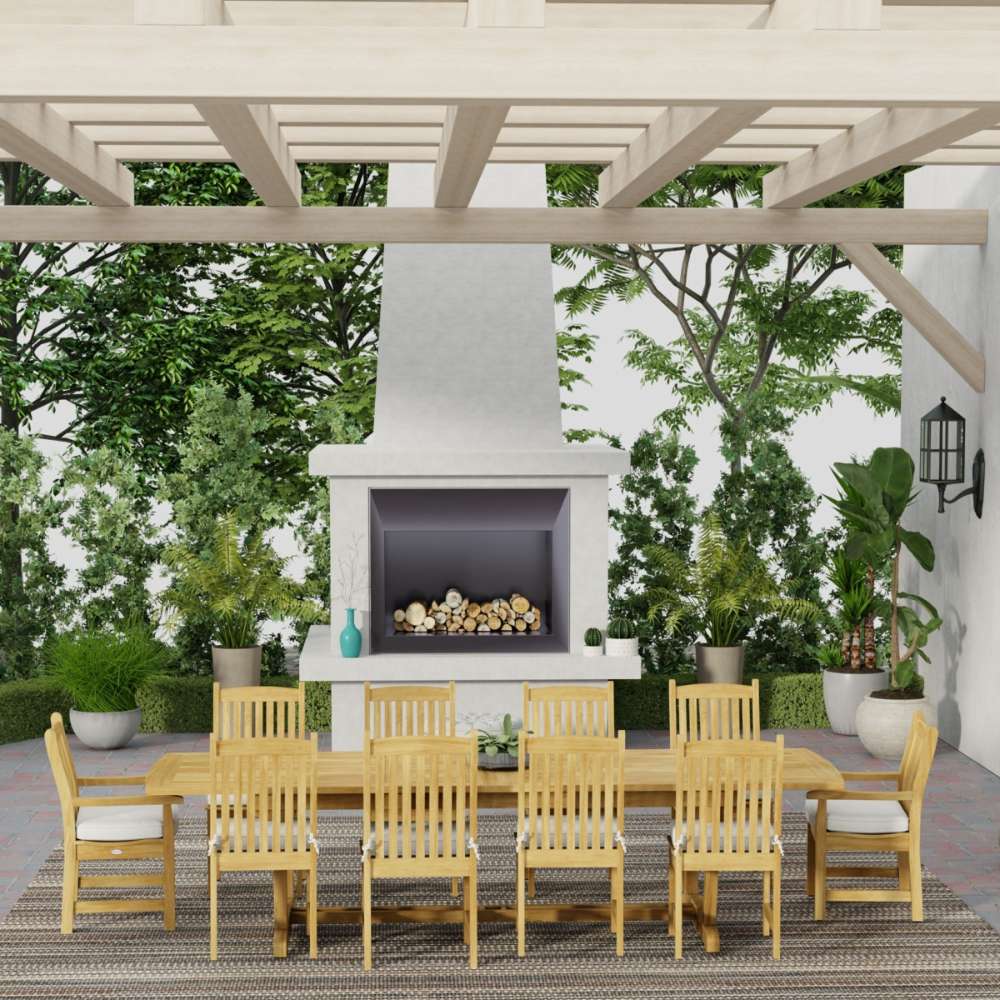 Westminster Teak Veranda 11pc Teak Dining Set arranged on a covered patio with a fireplace, featuring a long table and matching chairs surrounded by greenery