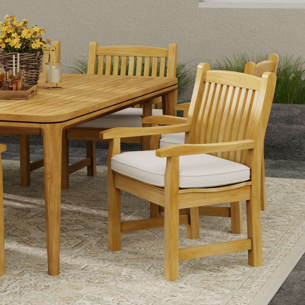 Westminster Teak Veranda Teak Armchair is displayed beside a matching wooden outdoor table on a patio, creating a warm and inviting dining setup