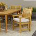 Westminster Teak Veranda Teak Armchair is displayed beside a matching wooden outdoor table on a patio, creating a warm and inviting dining setup