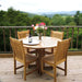 Westminster Teak Veranda Teak Dining Chair surrounds a round teak table on a deck with a mountain view, styled with flowers, wine, and glassware