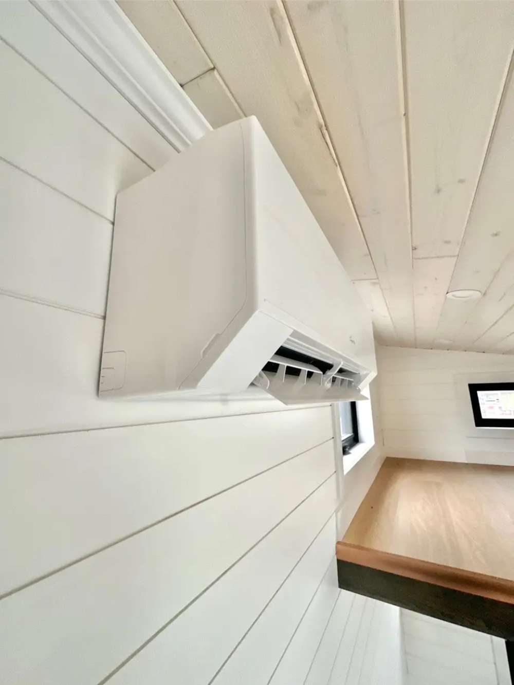 White mini-split air conditioner is mounted high on the wall inside Sawmill Structures Wanderlove Tiny Home for efficient climate control