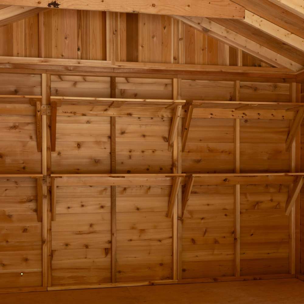 Wide view of a wooden shed interior shows multiple empty Outdoor Living Today 8ft Western Red Cedar Shed Shelves (Set of 3) mounted neatly along the wall