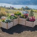 Wide view shows a tiered flower bed on a hillside by a lake, centering the Outdoor Living Today 5.5×2 Tiered Cedar L-Shaped Raised Garden Bed