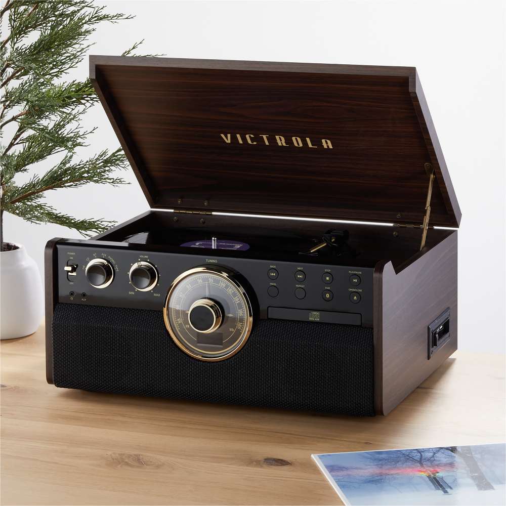 With its lid open, the Victrola Empire Bluetooth Record Player plays a vinyl record beside a plant