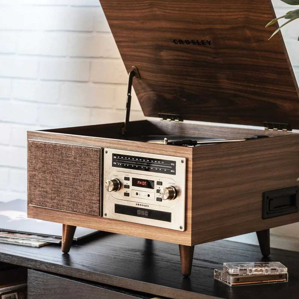 With a vintage wooden design, the Crosley Serenade 8-In-1 Record Player - Walnut features a lifted lid revealing a vinyl turntable and built-in speakers