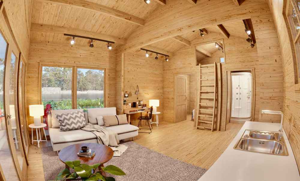 Wood-paneled living space in the Sawmill Structures Edwin Lake House PLUS 70MM Garden Room shows a white sectional sofa, kitchen area, and small workspace