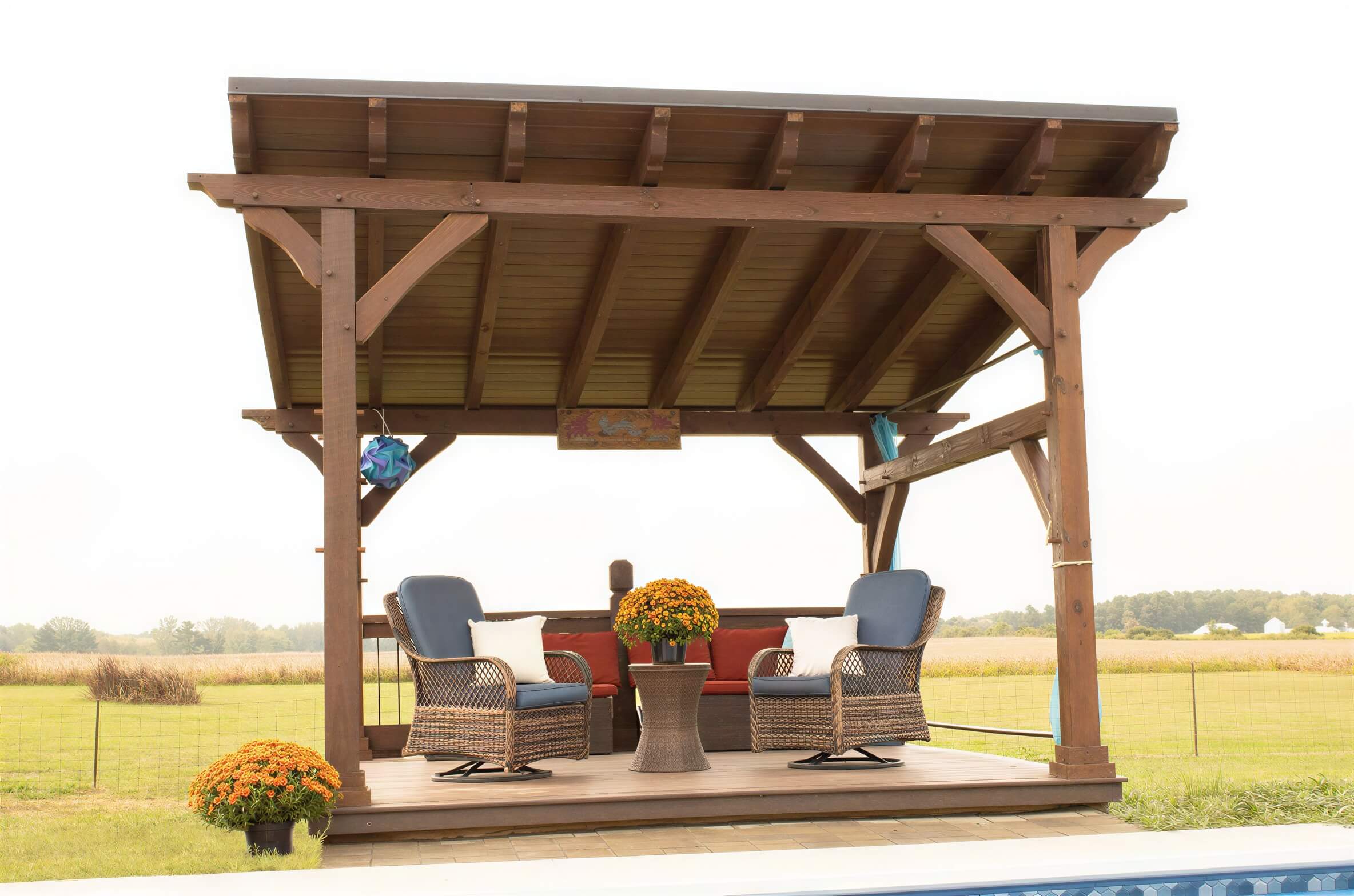 Wooden Brookside Timber Frame Rose Beam Pavilion on a deck with seating, set in an open countryside view