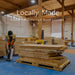 Worker in a workshop stacks and prepares wood panels, representing the local craftsmanship behind Outdoor Living Today Western Red Cedar 8x5 Grill Gazebo
