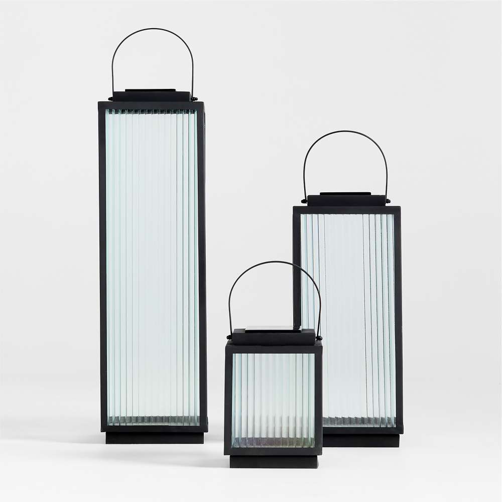 All three sizes of the Crate & Barrel Alfresco Black Metal and Glass LED Solar Outdoor Lantern shown together in a front view