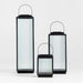 All three sizes of the Crate & Barrel Alfresco Black Metal and Glass LED Solar Outdoor Lantern shown together in a front view