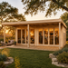 Rectangular light wood studio with glass doors and a deck, featuring people inside a lit lounge and bar area at sunset.