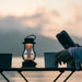 Black Crate & Barrel Balmuda LED Rechargeable Outdoor Lantern shown in a styled setting, cordless and portable by its metal carry handle