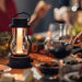 Black Crate & Barrel Balmuda LED Rechargeable Outdoor Lantern shown in a styled setting, its hidden LED glowing warmly down the central tube