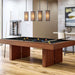 Black Crate & Barrel Walnut Pool Table with Wall Rack and Accessories at an angle in a game room under four pendant lights with coloured balls on the black felt and a wall cue rack behind