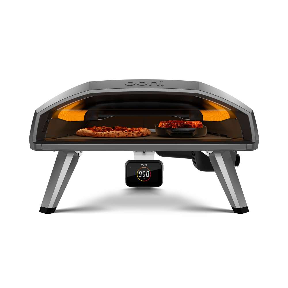 Black Ooni Koda 2 Pro Pizza Oven front view with a pepperoni pizza and a tray of roasting food side by side on the stone.