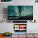 Black Sonos Ray Sound Bar sitting in front of a television showing the northern lights on a white sideboard in a living room with a striped rug